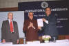 H.E. Mr. Prithviraj Chavan, M.P., Minister of State in the Prime Minister's Office, displaying a copy of the Indian edition of Hans Koechler's book "Global Justice or Global Revenge?" to the delegates of the International Conference on "The Emerging Trends in International Criminal Jurisprudence" organized by the Indian Society of International Law (ISIL) in New Delhi, 11 December 2005. With him at the podium at Krishna Menon Bhawan in New Delhi: Shri Ram Niwas Mirdha, President of ISIL, center, and Dr Hans Koechler, President of the I.P.O.